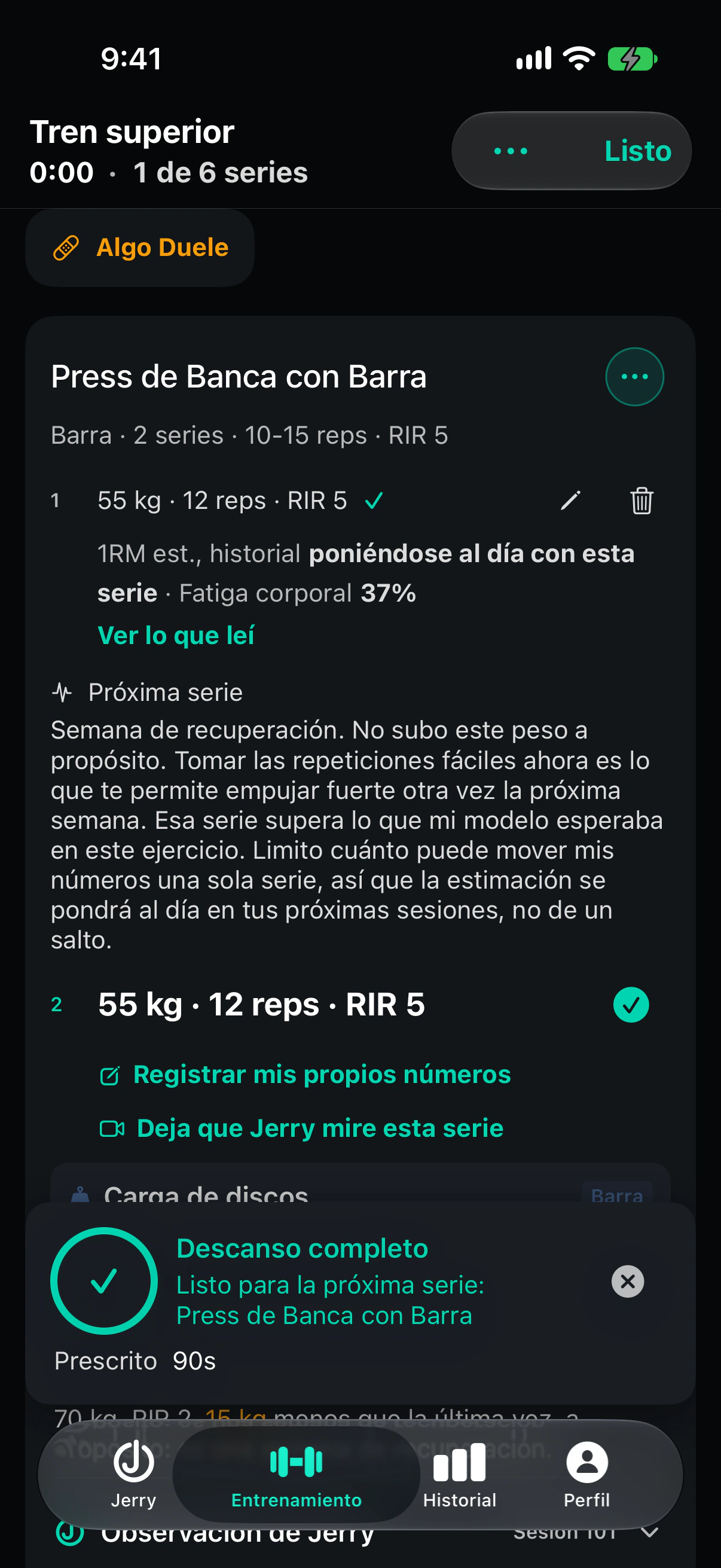 La misma consola después de registrar la serie 1. Debajo de la serie registrada, una nota de Próxima serie dice que es semana de recuperación y que no sube el peso a propósito, que la serie superó lo que su modelo del ejercicio esperaba, y que mueve su estimación a lo largo de las próximas sesiones y no de un salto. La tarjeta de descanso dice Descanso completo con 90 segundos prescritos.